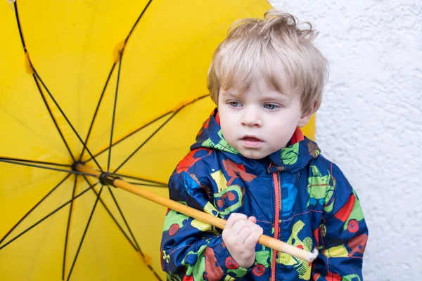 Mignon garçon tout-petit avec parapluie jaune, à l'extérieur — Photo