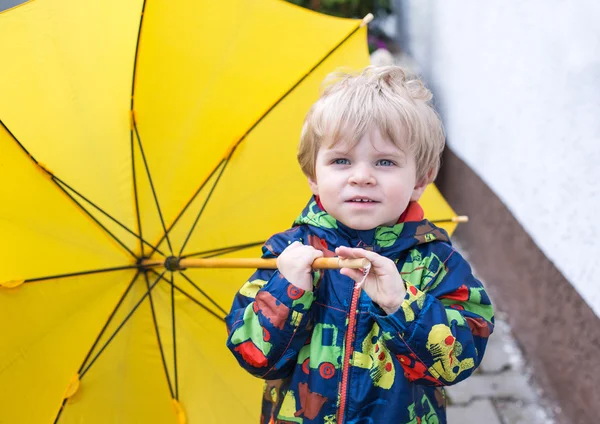 Chłopak ładny maluch z żółty parasol, na zewnątrz — Zdjęcie stockowe