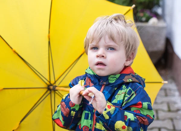Chłopak ładny maluch z żółty parasol, na zewnątrz — Zdjęcie stockowe