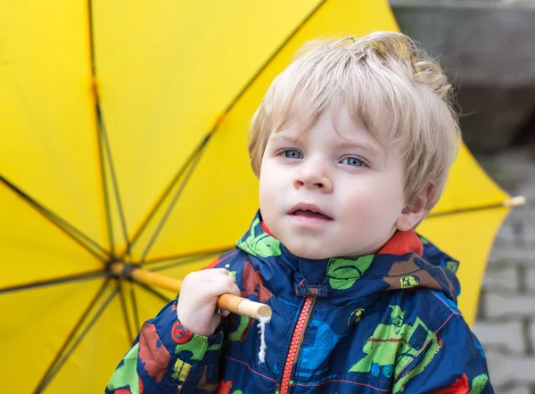 Mignon garçon tout-petit avec parapluie jaune, à l'extérieur — Photo