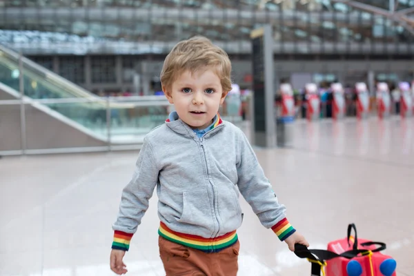 Menino sentado em uma mala no aeroporto — Fotografia de Stock