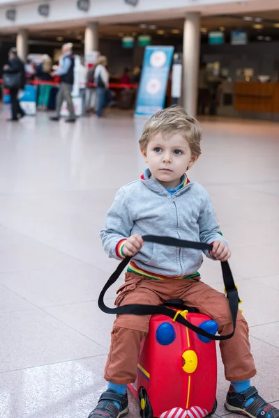 Peuter jongen zittend op een koffer op luchthaven — Stockfoto