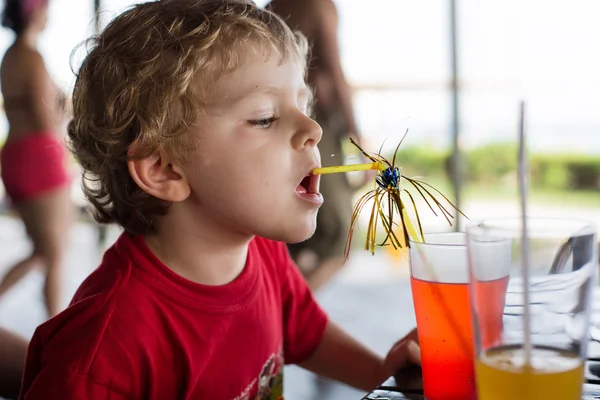 Счастливый мальчик, пьющий апельсиновый сок с соломой — стоковое фото
