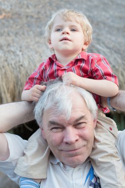 Dede torunu omuzları açık havada binmek vererek