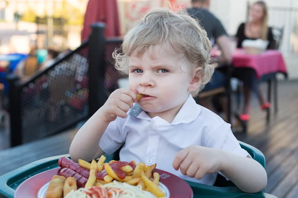 Ładny chłopczyk jedzenia frytek w lecie — Zdjęcie stockowe