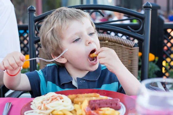 Bonito menino comendo batatas fritas no verão — Fotografia de Stock