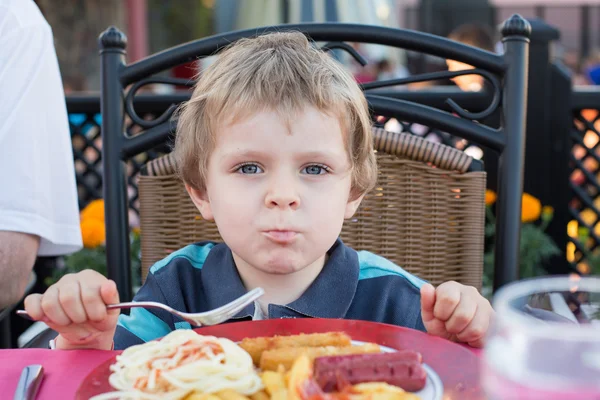 Cute little boy eating french fries in summer — Stock Photo, Image