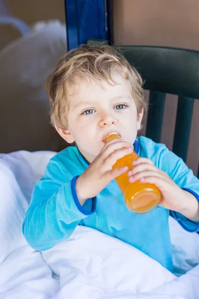 Menino feliz bebendo suco de laranja na varanda — Fotografia de Stock