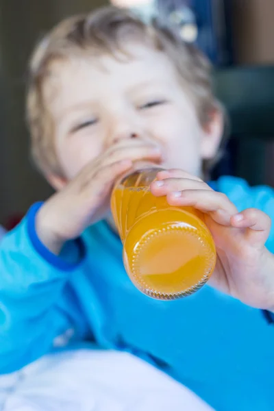 Happy little boy drinking orange juice on balcony — Stock Photo, Image