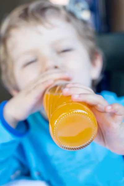 Fröhlicher kleiner Junge trinkt Orangensaft auf Balkon — Stockfoto