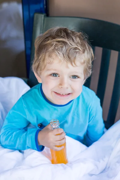 Glad liten pojke dricka apelsinjuice på balkong — Stockfoto