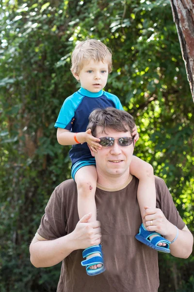 Gelukkig jonge vader geven kleine jongen een ritje op de schouders — Stockfoto