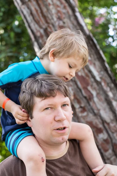 Glad ung pappa ger liten pojke en tur på axlarna — Stockfoto