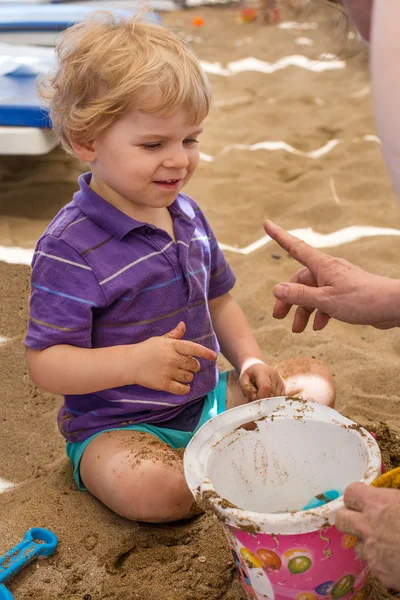 Kum ve oyuncak oynarken küçük yürümeye başlayan çocuk — Stok fotoğraf