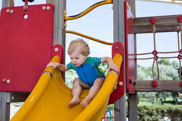 Piccolo bambino seduto sul parco giochi — Foto Stock