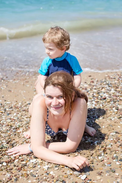 Young mother and little son having fun on beach Stock Picture