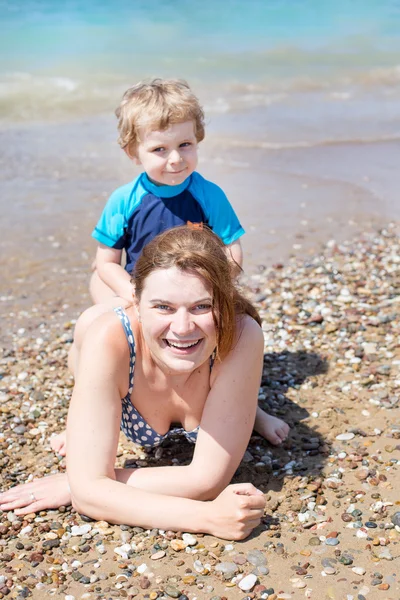 Young mother and little son having fun on beach Royalty Free Stock Images