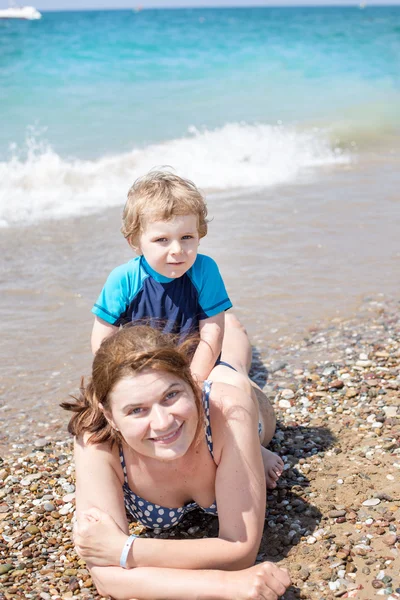 Young mother and little son having fun on beach Stock Photo