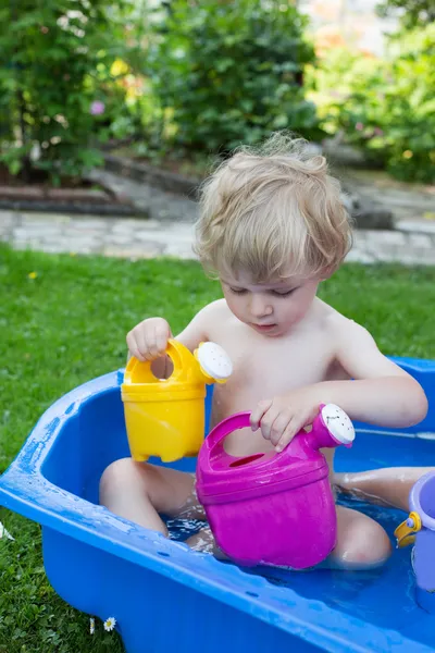 Little blond toddler boy playing with water in summer — Stock Photo, Image