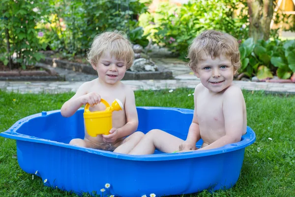 Два брата и сестры веселятся с водой летом — стоковое фото