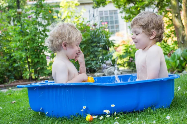 To søsken som morer seg med vann om sommeren – stockfoto