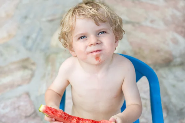 Entzückender kleiner Junge mit blonden Haaren, der Wassermelone isst — Stockfoto