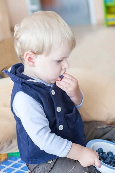 Menino pequeno comendo mirtilo em casa — Fotografia de Stock