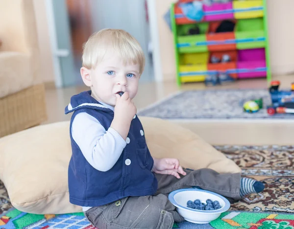 Menino pequeno comendo mirtilo em casa — Fotografia de Stock