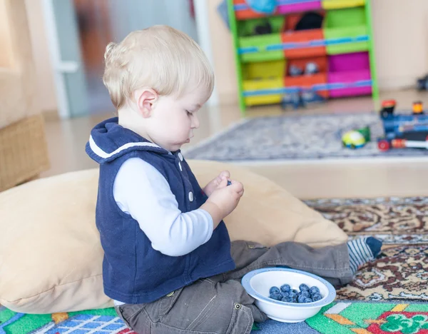 Piccolo bambino ragazzo mangiare mirtillo al coperto — Foto Stock