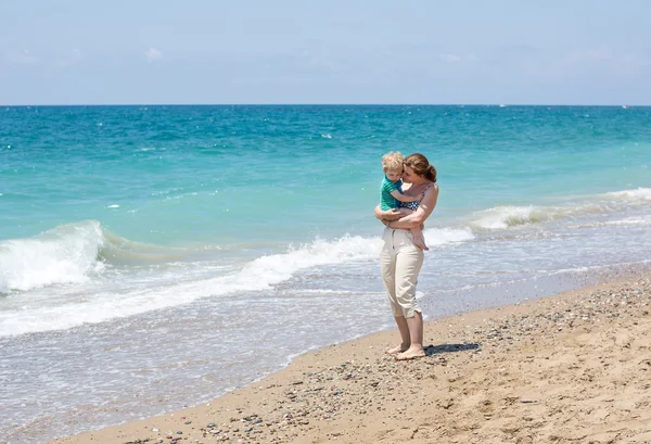 Gelukkig moeder en baby zoontje plezier op strandvakantie — Stockfoto