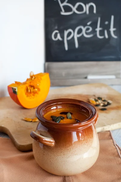 Zuppa di crema vegetale di zucca in ciotola marrone con pezzo di zucca — Foto Stock