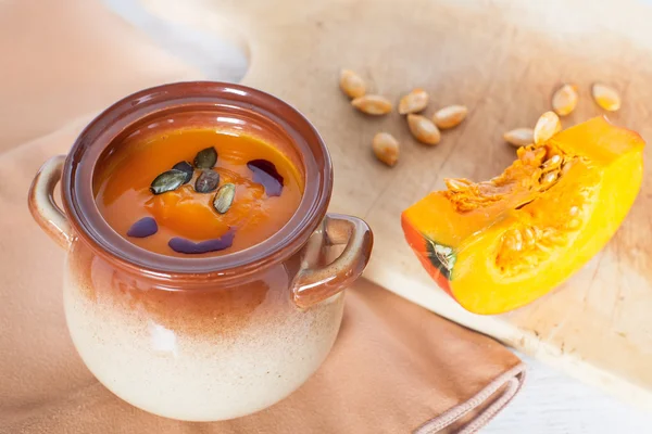 Sopa de crema vegetal de calabaza en un tazón marrón con trozo de calabaza —  Fotos de Stock