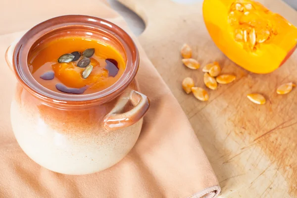 Soupe à la crème de légumes à la citrouille dans un bol brun avec citrouille en morceaux — Photo