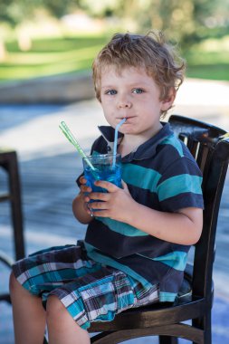 Café kokteyl ile yüksek sandalye üzerinde oturan sarışın çocuk