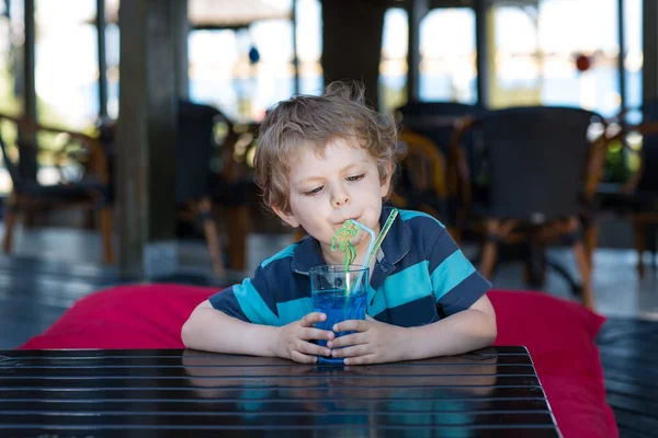 Маленький блондин, сидящий на стуле в кафе с коктейлем — стоковое фото
