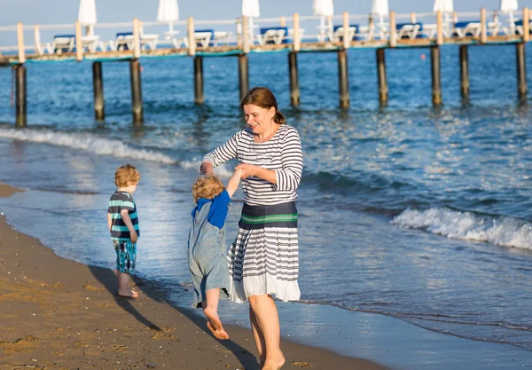 Szczęśliwa matka i dwoje dzieci trochę spaceru na plaży — Zdjęcie stockowe