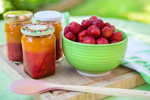 Marmellata di fragole fatta in casa in diversi barattoli e fragola fresca matura — Foto Stock