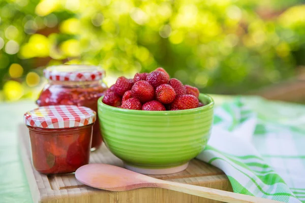 Domowy dżem truskawkowy w różnych słoikach i świeże, dojrzałe strawbe — Zdjęcie stockowe