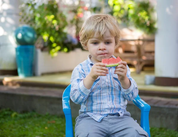 Adorable little toddler boy with blond hairs eating watermelon i — Stock Photo, Image