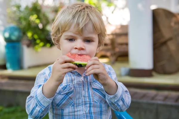 Adorável menino criança com cabelos loiros comendo melancia i — Fotografia de Stock