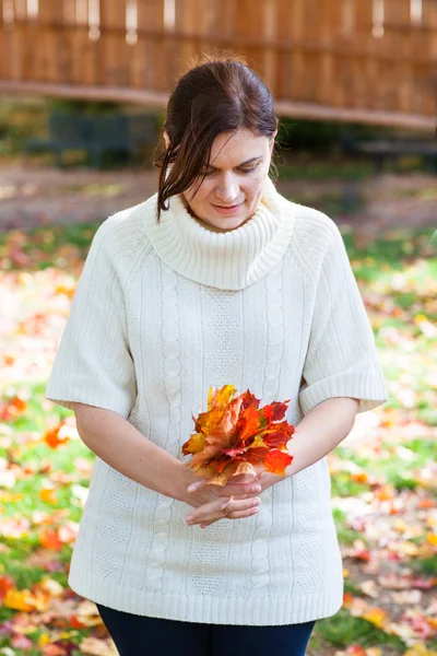 Vacker flicka i parken hösten samlar löv — Stockfoto