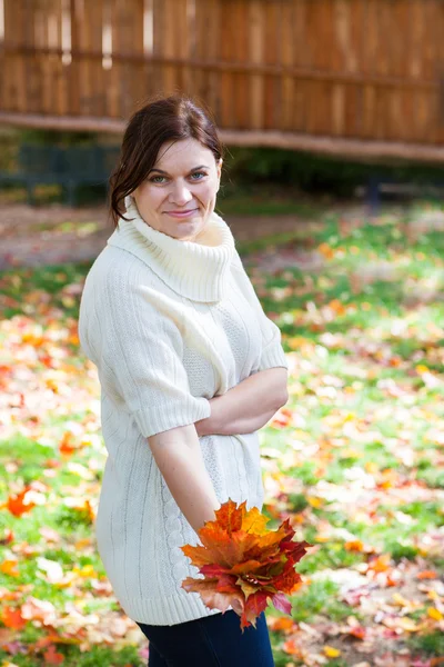 Mooi meisje in de herfst park verzamelt bladeren — Stockfoto