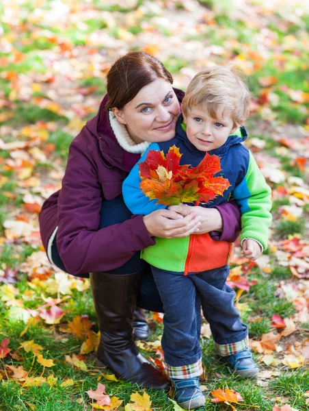 Little toddler boy and young mother in the autumn park — Stock Photo, Image