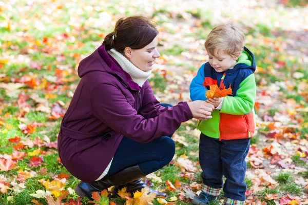 Little toddler boy and young mother in the autumn park — Stock Photo, Image