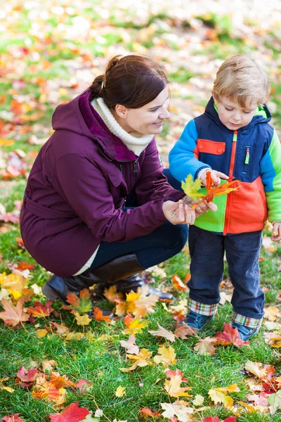 Kleines Kleinkind und junge Mutter im Herbstpark — Stockfoto