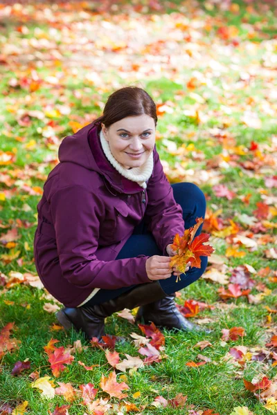 Menina bonita no parque de outono recolhe folhas — Fotografia de Stock
