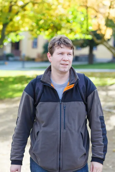 Beautiful young man in park on sunny autumn day — Stock Photo, Image