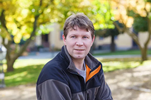 Beautiful young man in park on sunny autumn day — Stock Photo, Image