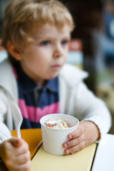 Ładny mały chłopiec jedzenie jogurt mrożony lody w kawiarni — Zdjęcie stockowe