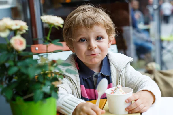 Adorable niño comiendo helado de yogur congelado en la cafetería —  Fotos de Stock